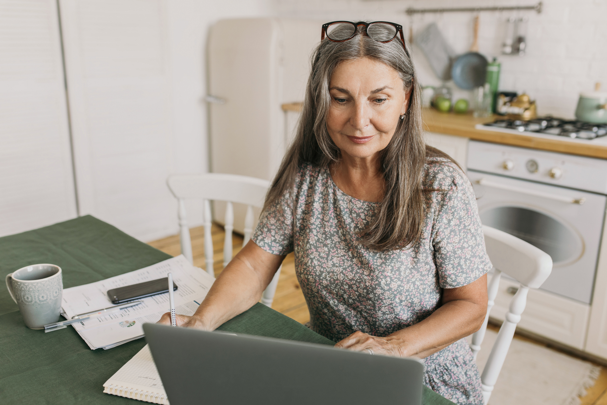 elderly woman sitting in kitchen in front of laptop